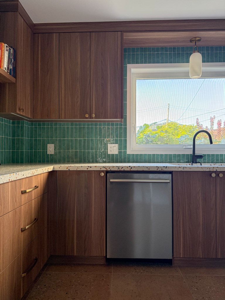 Walnut kitchen cabinetry with green tile backsplash, open shelving and terrazzo countertop.